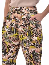 Pantalón babucha de tiro alto con cintura fruncida y lazo para ajustar. Estampado de hojas tropicales en tonos naranja y marrón sobre fondo blanco.