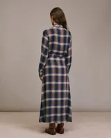 Vestido largo camisero con estampado a cuadros en tonos azul, marrón y beige. Presenta cuello camisero con volantes y mangas largas. Incluye cinturón de la misma tela para ajustar a la cintura.