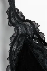 Soutien de encaje negro con copas acolchadas, diseño triangular y bordes festoneados. Cuenta con breteles ajustables y cierre posterior.
