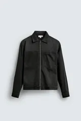 Sobrecamisa de denim de algodón, color negro lavado, con cuello solapa, cierre frontal de cremallera, manga larga con puño abotonado y bolsillo plastrón en el pecho.