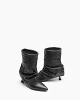 Bota de cuero negro con caña corta arrugada y taco fino.