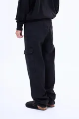 Pantalón cargo de denim negro con corte holgado, bolsillos laterales con solapa y cierre frontal con botón.