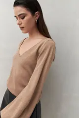 Top color dorado con escote en V y mangas abullonadas. Tejido con acabado metalizado.