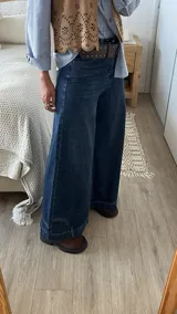 Jean de corte ancho y tiro medio, confeccionado en denim azul oscuro sin lycra. Presenta un diseño de pierna recta y holgada con costuras reforzadas.