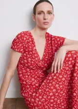 Vestido midi rojo con estampado floral blanco, cuello en V, manga corta y detalle de nudo frontal en el pecho.