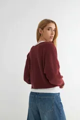 Sweater de punto negro, de corte holgado y diseño cropped, con cuello redondo y mangas largas.