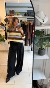 Sweater tejido de punto con diseño a rayas horizontales en tonos amarillo, celeste y marrón. Presenta un cuello polo con escote en V, mangas largas y un corte holgado.