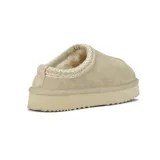 Pantufla tipo mule de cuero gamuzado color beige, con detalle de costura decorativa en el borde superior y suela de plataforma plana con base dentada.