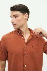 Camisa de manga corta confeccionada en una mezcla de lino y algodón, con cuello clásico, cierre frontal de botones y bolsillo en el pecho con logo bordado.