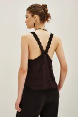 Top negro con escote en V y tirantes finos, ambos con detalles de encaje. Presenta un diseño de cadenas bordadas con cuentas en la parte frontal.