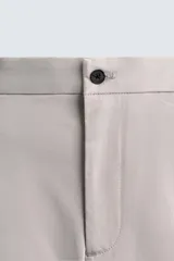 Pantalón chino de corte regular fit, confeccionado en tejido de algodón con elasticidad. Presenta bolsillos frontales, bolsillos traseros de vivo y cierre frontal con cremallera y botón.