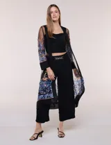 Cardigan tipo kimono largo de tul blanco semitransparente, con frente abierto y mangas largas. Presenta vistosos bordados florales multicolor en mangas, dobladillo y laterales.