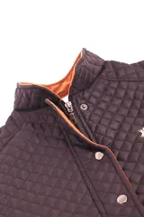Chaleco capitoneado color rosa con cuello alto, cierre frontal con botones a presión y bolsillos laterales. Presenta un diseño acolchado con costuras en forma de rombos.