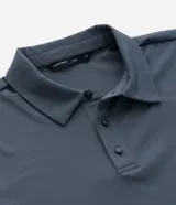 Camisa polo masculina de manga corta, confeccionada en tejido técnico de poliamida con elastano. Presenta cuello inglés con cierre de botones y diseño liso en color marrón, con tecnología de secado rápido y confort térmico.
