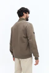 Campera de algodón con cierre frontal, cuello alto en color verde oliva y cuerpo texturado con patrón de espiga en tono marrón topo. Las mangas son lisas y del mismo tono que el cuerpo. Presenta un pequeño logo bordado en el pecho.