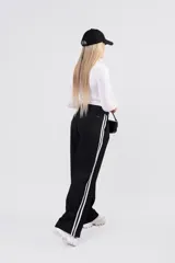 Pantalon de vestir gris con detalle de franjas laterales negras y etiqueta de marca Dolce en el bolsillo trasero.