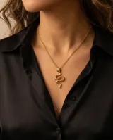 Collar de acero con baño de oro, compuesto por una cadena fina de eslabones y un dije en forma de serpiente con detalles brillantes en la cabeza.