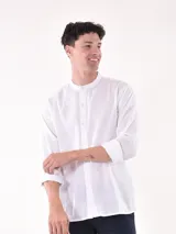 Camisa blanca de manga larga con cuello mao y cierre frontal de botones.