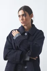 Tapado corto de paño con textura, color marrón, de corte recto y silueta estructurada. Presenta cuello camisero, cierre frontal con botones grandes y mangas largas con detalle de trabas en los puños.