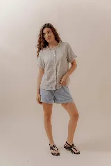 Camisa de manga corta color beige, con cuello fruncido y cierre frontal de botones.