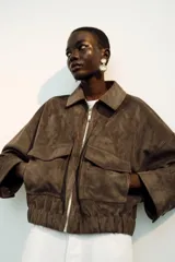 Aros colgantes de diseño circular doble, con piedras grises engarzadas en marcos dorados y bordes decorados con pequeños cristales oscuros.