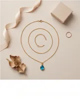 Collar de bronce con cadena fina de eslabones y un dije colgante en forma de lágrima con piedra azul translúcida en bisel dorado.