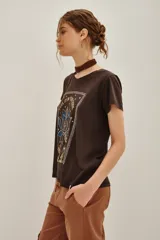 Remera de algodón color marrón oscuro con estampa frontal de estilo místico que incluye manos en posición de mudra, una flor de loto y la frase 'Feel it in your soul'.
