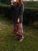 Cartera de cuero vacuno con pelo en diseño animal print similar a piel de ciervo, silueta triangular y asa integrada.