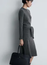 Jersey de punto gris de cuello redondo y manga larga, con diseño recto y detalle de lazo anudado en la cintura.