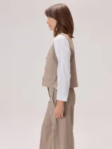 Chaleco negro sin mangas, de corte recto y largo a la cintura, con cuello redondo y cierre frontal oculto.