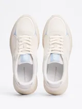 Zapatillas deportivas Tommy Hilfiger de corte bajo, color blanco con detalles en celeste y plateado. Presentan paneles de malla y superposiciones de gamuza, con el monograma TH en la lengüeta y el lateral.