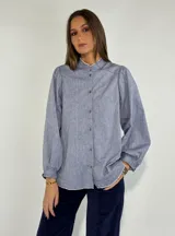 Camisa celeste con cuello mao, mangas largas abullonadas y cierre frontal con botones.