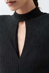 Mono largo negro con textura amasada, cuello mao con abertura en forma de gota, mangas largas y cinturón plateado de eslabones.