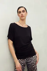 Remera negra de manga corta, confeccionada en modal, con cuello bote y frunces laterales.
