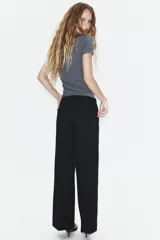 Pantalón de tiro bajo y corte recto, color marrón oscuro. Presenta bolsillos laterales, cierre frontal con cremallera y gancho metálico, y un cinturón integrado del mismo tejido con hebilla metálica.