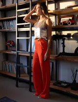 Pantalón naranja de crepe elastizado, corte recto, con bolsillos delanteros y apliques de botones metálicos.