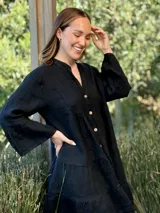 Vestido amplio de lino color verde lima, con cuello mao y abertura frontal con botones de coco. Presenta un diseño con canesú fruncido y volados en los puños de las mangas largas.