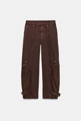 Pantalón cargo de tiro medio confeccionado en algodón, con diseño de pierna tipo barril. Presenta bolsillos laterales y bolsillos de plastrón con solapa en las piernas, además de un bajo ajustable mediante trabillas y hebilla metálica.