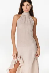Vestido midi marrón de lino italiano, con cuello halter, sin mangas y diseño asimétrico con volados en el ruedo.