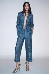 Blazer azul de encaje floral, con cuello solapa, manga larga con hombreras, falsos bolsillos delanteros y cierre frontal con un botón.
