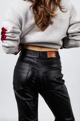 Pantalón de tiro alto color negro metalizado, de gabardina elastizada, con tajos en el frente.