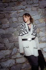 Saco tejido de punto con diseño de guarda inca en la parte superior. Presenta bolsillos frontales con detalles de tiras de cuero y flecos. De corte recto y largo medio, con terminaciones en tejido acanalado.