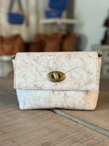 Bandolera de cuero color beige con efecto craquelado marrón, solapa frontal con cierre metálico de vuelta y herrajes en tono bronce envejecido.