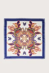 Pañuelo cuadrado con estampado floral y geométrico central en tonos naranja, amarillo, verde y azul, enmarcado por un borde azul marino con líneas blancas. Presenta un acabado sedoso.