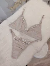 Conjunto de lencería compuesto por un bralette triangular y una bombacha tipo colaless, confeccionados en algodón color nude con delicados detalles de encaje en los bordes.