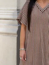 Vestido largo de tejido de punto con diseño de rayas verticales en blanco y negro. Presenta escote en V, mangas cortas y tajos laterales en el ruedo para mayor movimiento.