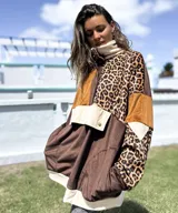 Buzo de estilo canguro con diseño de bloques de color y estampado animal print. Presenta una combinación de texturas en tonos marrón, chocolate y beige, con cuello alto, cierre frontal parcial con botones a presión y un bolsillo frontal grande con solapa.