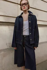 Cazadora de denim azul oscuro con cuello solapa, manga larga, cierre frontal con botones metálicos y bolsillos delanteros de plastrón.