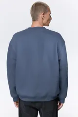 Buzo de cuello redondo confeccionado en mezcla de algodón con interior cepillado. Presenta diseño de hombros caídos y terminaciones acanaladas en puños y ruedo.