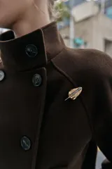 Pack de dos broches metálicos. Uno es un broche tipo aguja con forma de gota dorada y brillos incrustados. El otro es un broche tipo imperdible, con la parte superior plateada y el resto dorado.